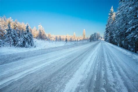 Empty Winter Road With Ice Slick And Snow Through Snowy Fields And