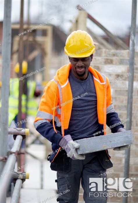 Male Construction Worker Carrying Brick At Construction Site Stock