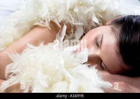 Naked Woman With Black Feather Boa Lying On Bed Putting Her Legs