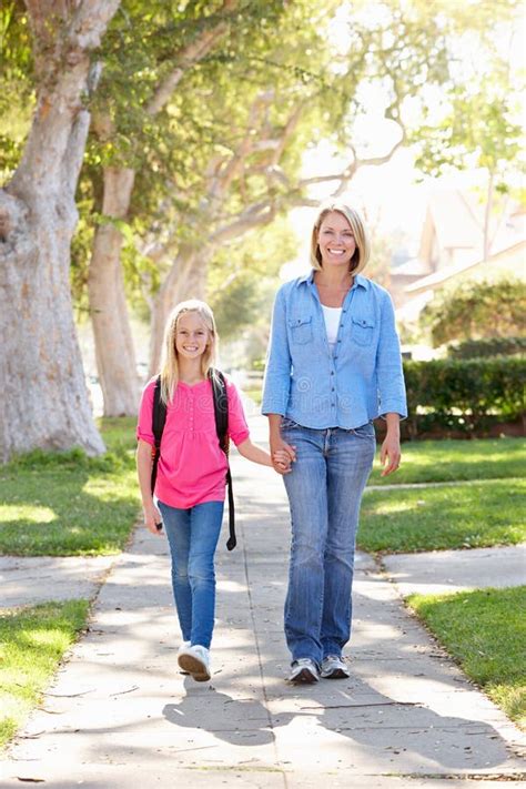 Mother And Daughter Walking To School On Suburban Street Stock Photo
