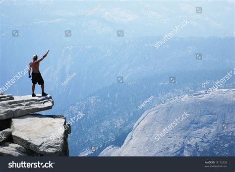 Man Standing On Top Of A Cliff With Arm Raised Stock Photo 15112228