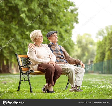 Senior Couple Sitting On A Bench In The Park Stock Photo By