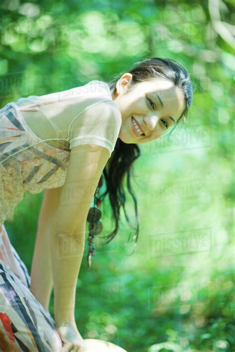 Young Woman Bending Over Outdoors Smiling At Camera Stock Photo