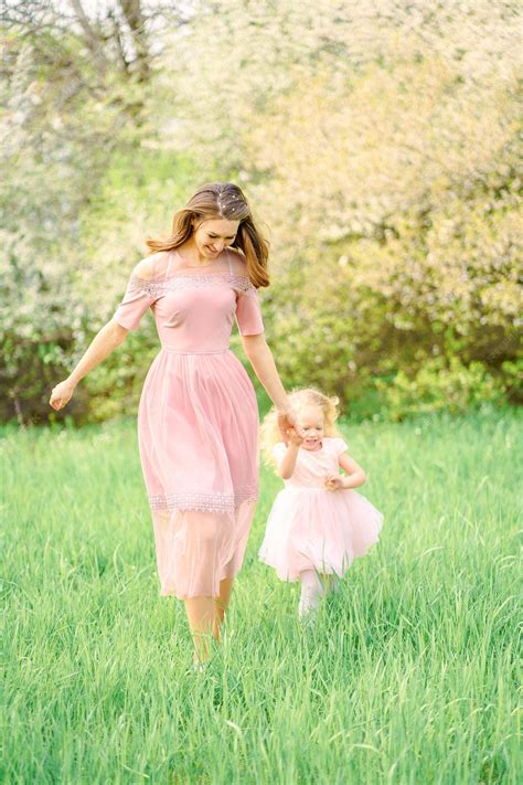 premium photo mom and daughter in pink dresses run in a spring meadow
