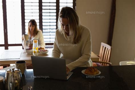 Lesbian Couple Using Laptop While Having Coffee In Kitchen 11092015723 の写真素材・イラスト素材｜アマナイメージズ