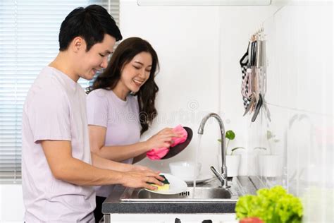Happy Couple Washing Dishes Together In The Sink In The Kitchen At Home Stock Image Image Of