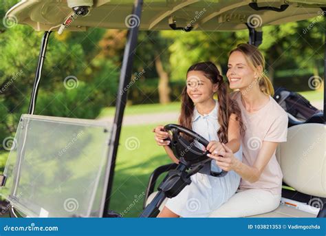 The Girl Is Sitting On The Lap Of A Woman Together They Control A Golf