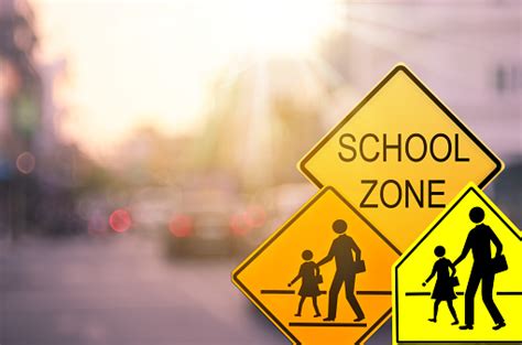 School Zone Warning Sign On Blur Traffic Road With Colorful Bokeh Light