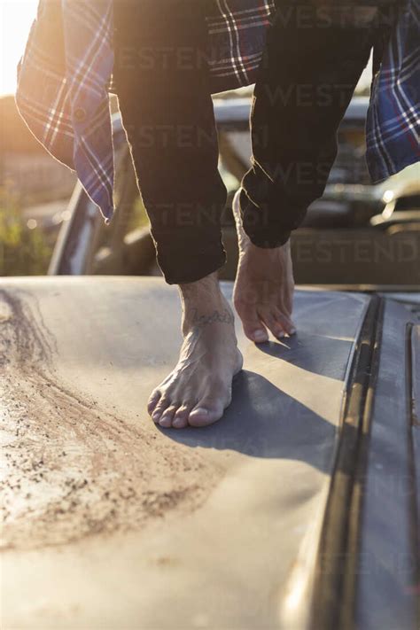 Young Man Walking Barefoot On Car Roof On A Scrapyard Stock Photo
