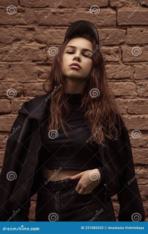 Young Thinking Teen Woman Looking Near The Red Brick Wall On The Street