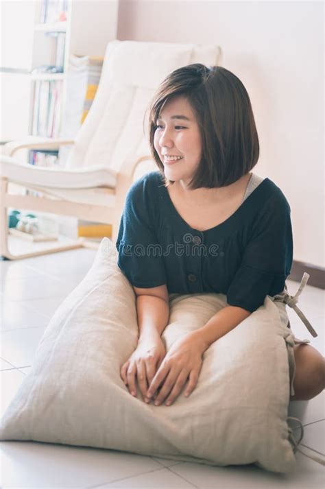 Young Asian Woman Sitting On The Floor In Living Room Stock Photo