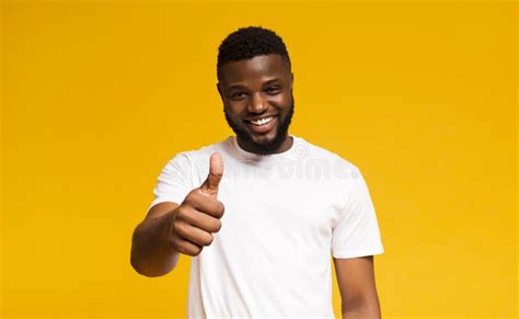 Happy Guy Showing Thumb Up And Smiling Over Yellow Background Stock