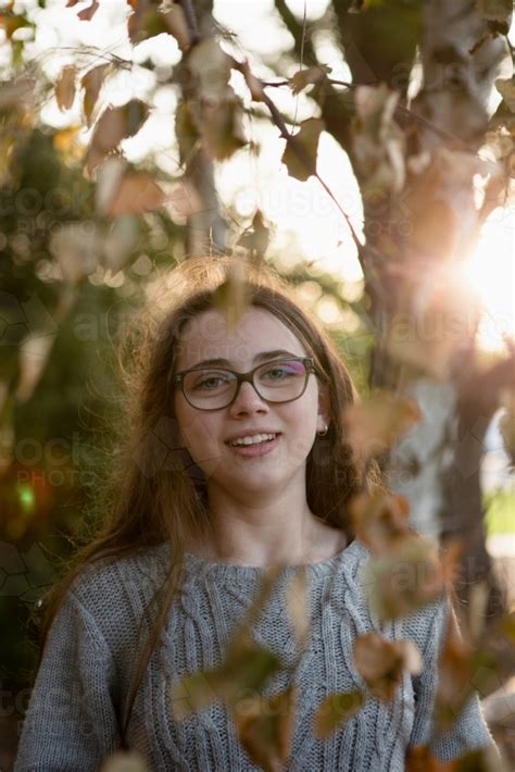 Image Of Young Teenage Girl Standing Near Trees With Leaves Framing The