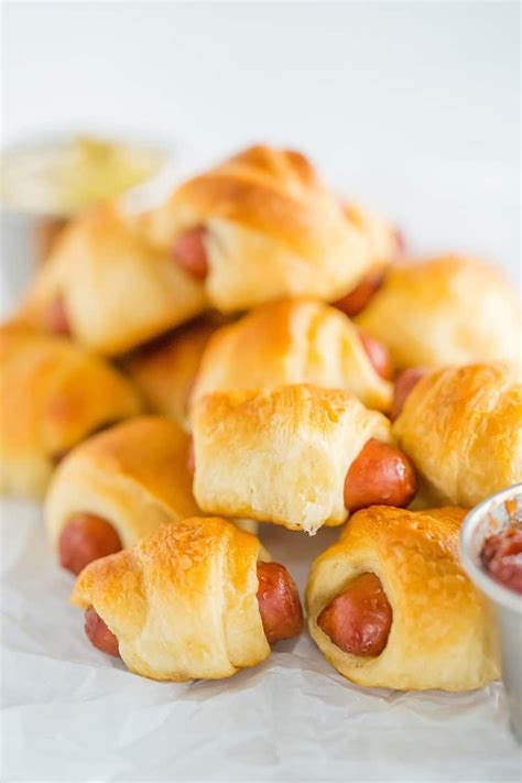 Mini Hot Dogs Wrapped In Crescent Rolls On Parchment Paper