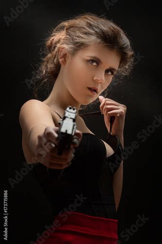 Beautiful Young Woman With Black Gun Aiming At Camera Stock Photo