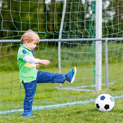 Two Little Sibling Boys Playing Soccer And Football On Field Stock