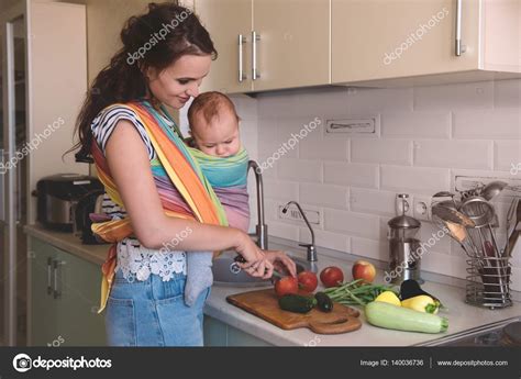 Mamá Cocinando En La Cocina Con El Bebé Fotografía De Stock