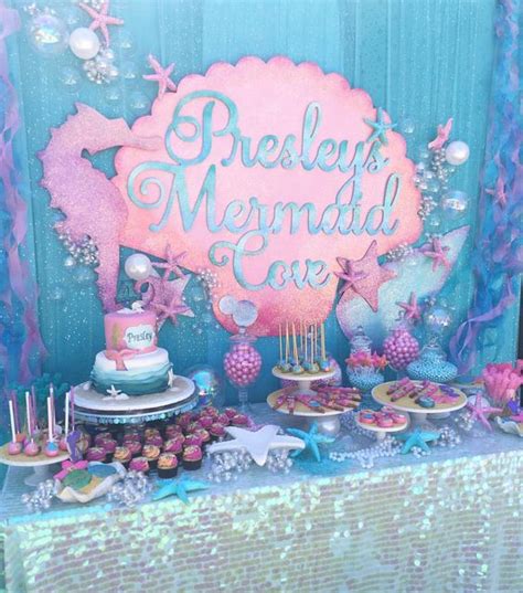 There Is A Mermaid Themed Cake And Cupcakes On The Table
