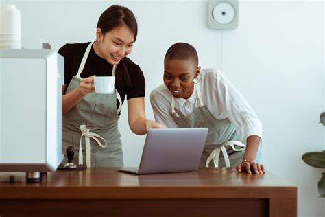 Cheerful Coworkers Using Laptop And Chatting In Kitchen · Free Stock Photo