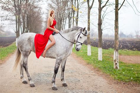 schöne mädchen in einem roten kleid auf einem weißen pferd reiten stockfoto und mehr bilder von