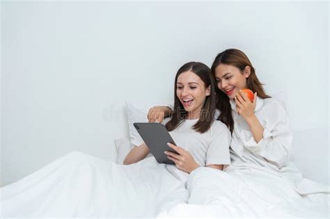 Young Asian Lesbian Couple Sitting On Bed During Happy Resting Time