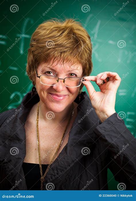 Smiling Teacher With Glasses Standing In Front Of Blackboard And Holding Book Royalty Free Stock