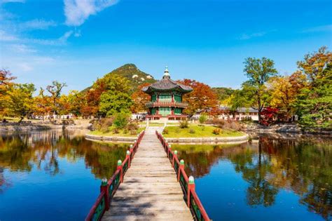A Wooden Bridge Over A Lake Leading To A Pavilion With A Pagoda In The