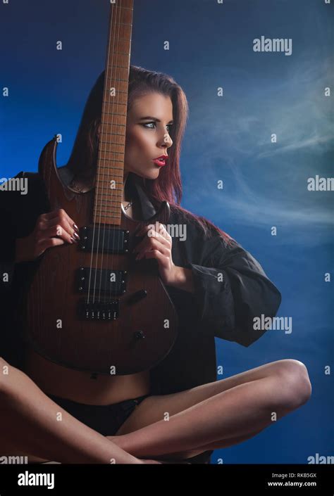 Sexy Girl With Electric Guitar In Blue Smoke Studio Shot Stock Photo
