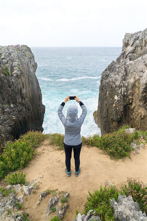 Woman Taking A Picture Of The Sea From A Cliff By Stocksy Contributor