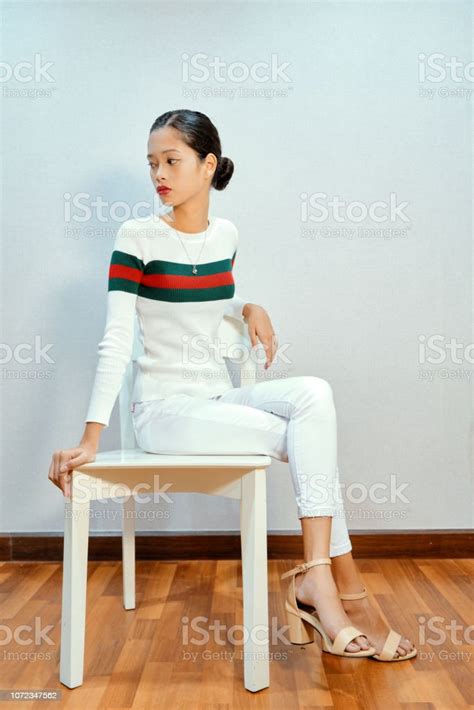 Beautiful Woman Posing Sitting On Chair Cross Legged Looking Away Stock