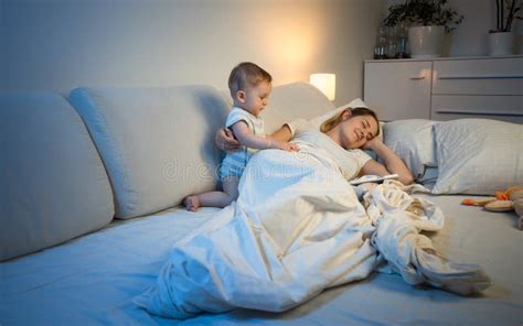 Sleepless Baby Boy Waking Up His Mother Sleeping In Bed Stock Photo