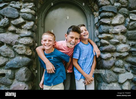 Oldest Brother Has Arms Around Younger Two While Laughing Stock Photo