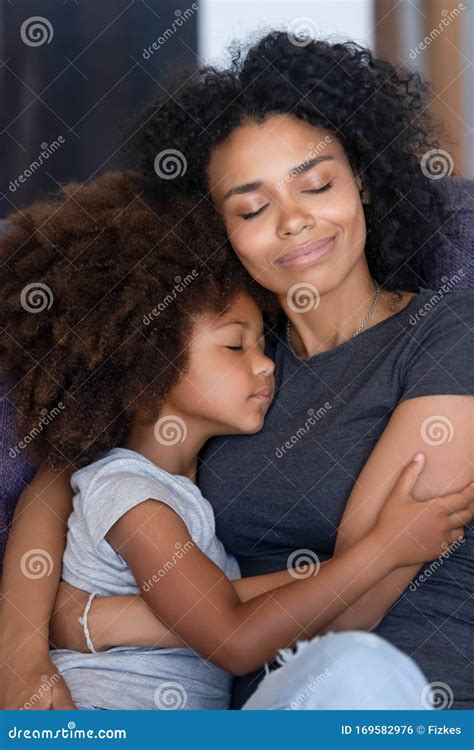 Black Mom And Small Daughter Hugging Tenderly On Couch Stock