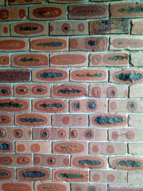 A Brick Wall That Has Been Painted Red And Brown With Black Dots On It