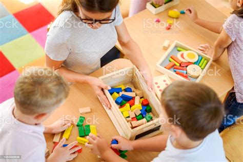 Preschool Teacher With Children Playing With Didactic Toys Stock Photo