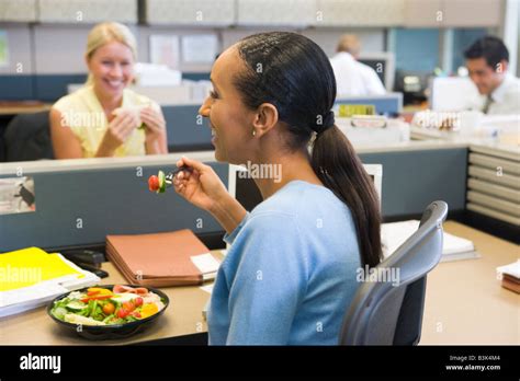 Businesswoman In Cubicle Eating Salad And Smiling Stock Photo Alamy