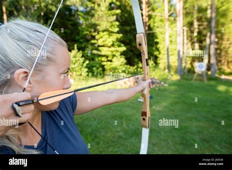 Female Archer Aiming Arrow At Target Board In Forest Stock Photo Alamy