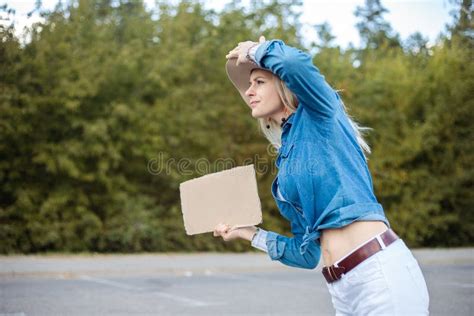 Exhausted Curious Blond Woman Hold Hat Hitchhiking With Blank Cardboard Plate And Look For Car