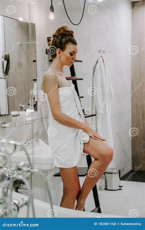 Beautiful Woman After A Shower In A White Towel Smears The Skin With Cream Stock Photo Image