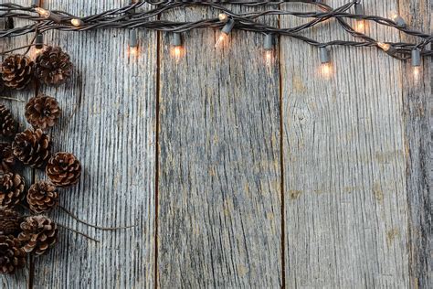 Christmas Lights And Pinecones On Rustic Wood Background Photograph By