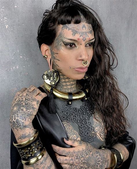 A Woman With Tattoos And Piercings On Her Face Is Posing For The Camera