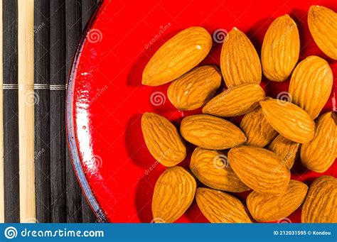 Almonds Nuts In A Red Saucer On A Bamboo Mat Closeup Stock Image