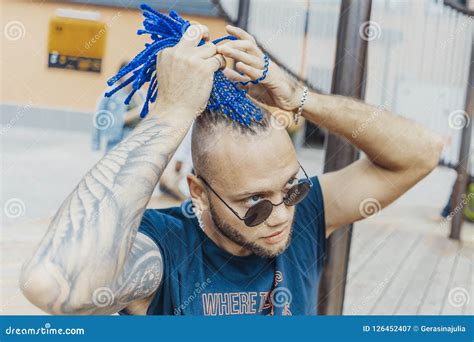 Young Attractive Man With Blue Dreadlocks Touching His Hair Stock