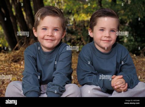 Young Identical Twin Boys In Matching Outfits While Outdoors Stock