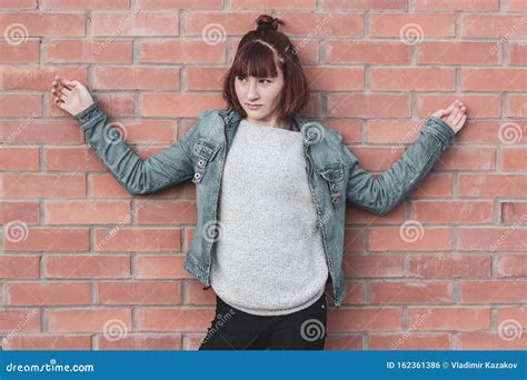 A Teenage Girl Is Leaning Against A Brick Wall With Her Hands Spread