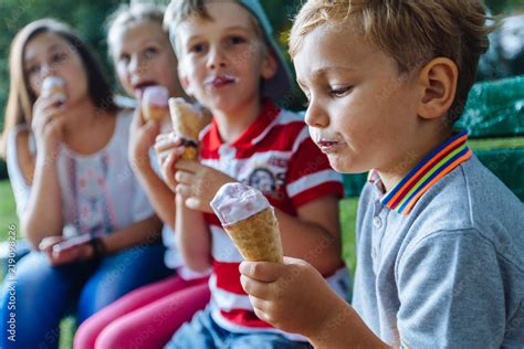 Team Of Four Different Age Happy Children Eating Ice Cream Outdoors In