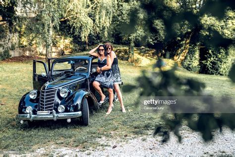Smiling Mature Lesbian Couple By Their Vintage Gangster Car High Res
