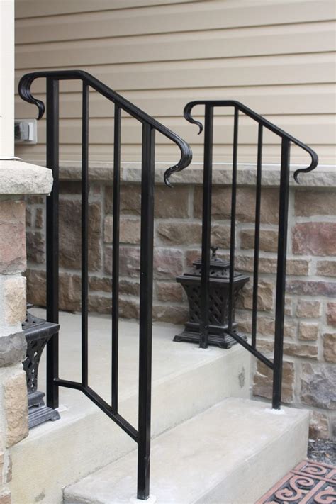 An Iron Hand Rail On The Steps Leading Up To A Door With A Lantern In It