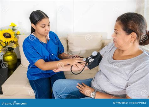 Hispanic Woman Doctor Uses Blood Pressure Check And Consults Woman