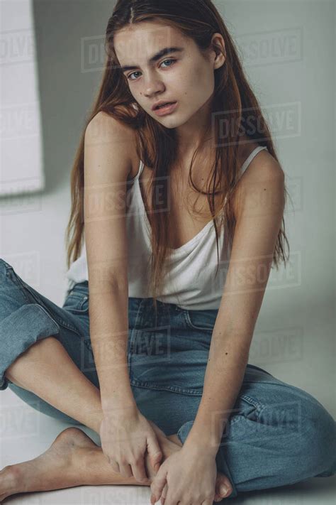 Full Length Portrait Of Teenage Girl Sitting On Floor Stock Photo